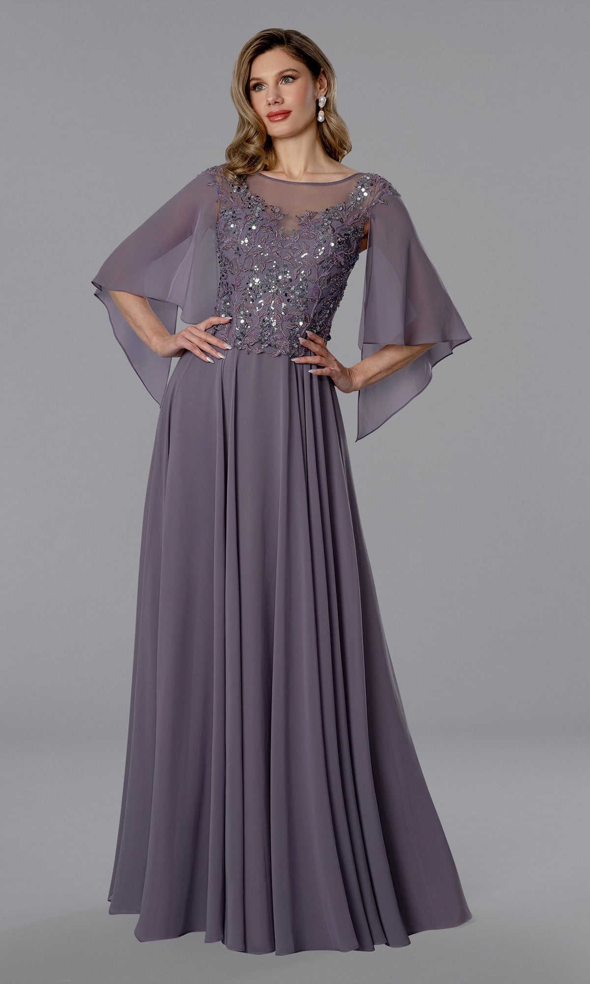 A woman in an amethyst Stella Couture 25351 long formal dress with sheer flutter sleeves and a sequin lace bodice stands against a plain gray background.